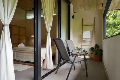 a bedroom with a bed and two chairs and a table at VED Beach Deluxe Studio 2, Steps to the Beach in Santa Teresa Beach