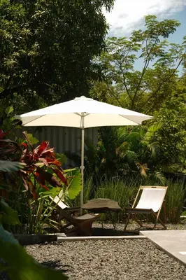a white umbrella and two chairs and a table at VED Beach Deluxe Studio 3, Steps to the Beach in Santa Teresa Beach