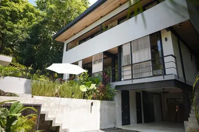 a white building with an umbrella on a balcony at VED Beach Deluxe Studio 3, Steps to the Beach in Santa Teresa Beach
