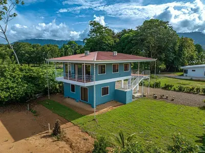 a blue house with a red roof on a yard at Luciernaga in Bahia