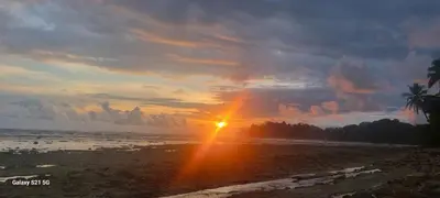 a sunset on a beach with the sun in the sky at Luciernaga in Bahia