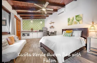 a bedroom with a large bed and a kitchen at Main Villa plus 2 casitas, 5 BR, POOL, canaba w grill in Tamarindo