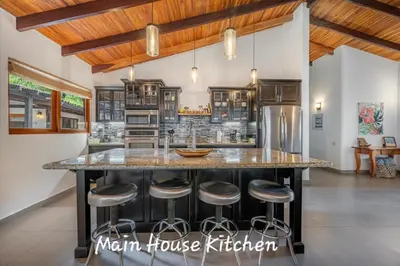 a kitchen with a large island with bar stools at Main Villa plus 2 casitas, 5 BR, POOL, canaba w grill in Tamarindo