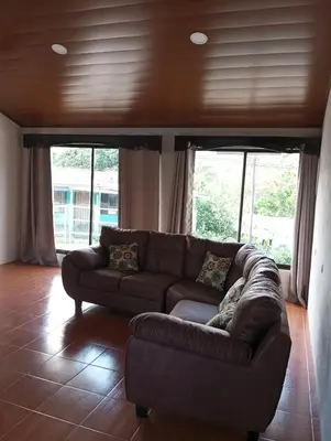 a brown couch in a living room with windows at Linda vista in Bijagua