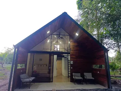 a small building with chairs and a balcony on it at Kono Rainbow Finca paraíso in Jiménez