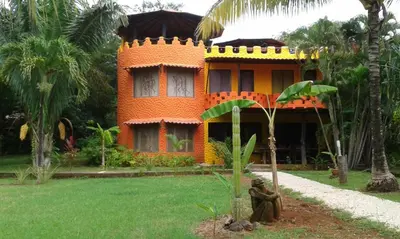 an orange house with a statue in front of it at El Castillo Divertido in Paraíso
