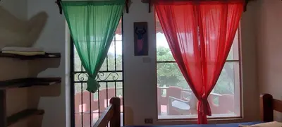 two windows with red and green curtains in a room at El Castillo Divertido in Paraíso