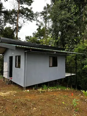 a small gray house with a porch and trees at Chava Lodge On Tenorio Rio Celeste in Rio Celeste