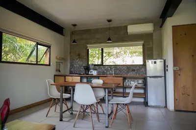 a kitchen with a table and chairs and a refrigerator at VED Beach Apt 5 - Steps to the Beach in Santa Teresa Beach