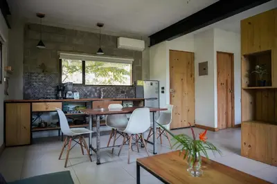 a kitchen with a table and some white chairs at VED Beach Apt 5 - Steps to the Beach in Santa Teresa Beach