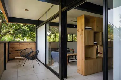 a room with a chair and a table and some windows at VED Beach Apt 5 - Steps to the Beach in Santa Teresa Beach