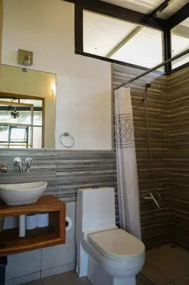 a bathroom with a toilet and a sink and a mirror at VED Beach Terrace Apt 6 - Steps to the Beach in Santa Teresa Beach