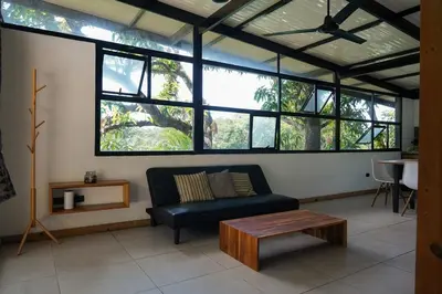 a living room with a black couch and a table at VED Beach Terrace Apt 6 - Steps to the Beach in Santa Teresa Beach
