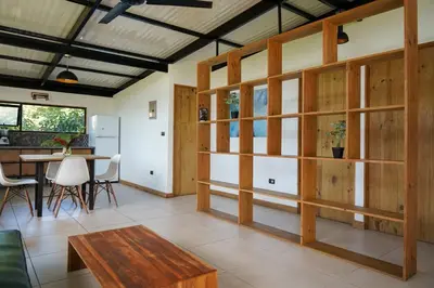 a living room with wooden walls and a table at VED Beach Terrace Apt 6 - Steps to the Beach in Santa Teresa Beach