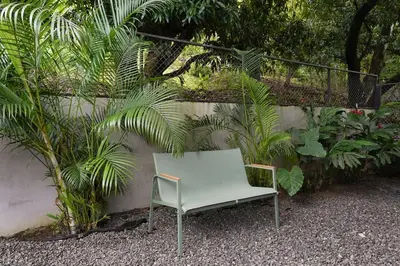a white chair sitting next to a wall with plants at VED Beach Apt 1 - 1BDR, Pool, Steps to the Beach in Santa Teresa Beach