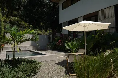 an umbrella and a chair next to a swimming pool at VED Beach Apt 1 - 1BDR, Pool, Steps to the Beach in Santa Teresa Beach