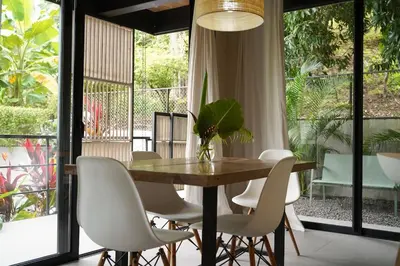 a dining room with a wooden table and white chairs at VED Beach Apt 1 - 1BDR, Pool, Steps to the Beach in Santa Teresa Beach
