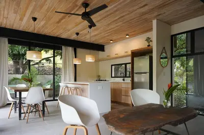 a kitchen with white chairs and a wooden ceiling at VED Beach Apt 1 - 1BDR, Pool, Steps to the Beach in Santa Teresa Beach