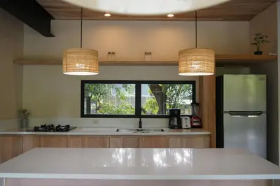 a kitchen with a refrigerator and two hanging lights at VED Beach Apt 1 - 1BDR, Pool, Steps to the Beach in Santa Teresa Beach