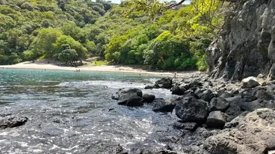 a river with rocks and a beach with people on it at Villa Prados del Rio 47 in Comunidad