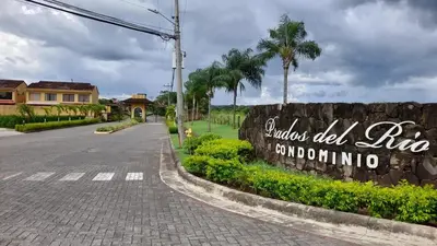 a sign on the side of a road with palm trees at Villa Prados del Rio 47 in Comunidad