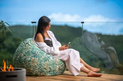 a woman sitting in a chair looking at her cell phone at Aves Monteverde Eco Lodge con jacuzzi in La Cruz
