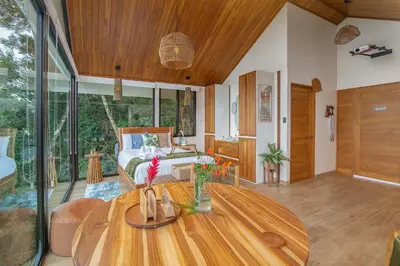 a living room with a wooden table and a bed at Aves Monteverde Eco Lodge con jacuzzi in La Cruz