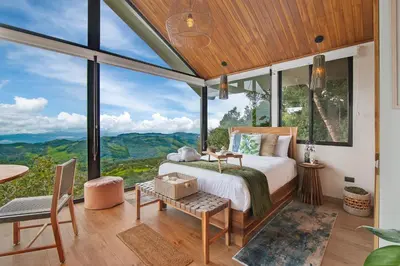 a bedroom with a bed and large windows at Aves Monteverde Eco Lodge con jacuzzi in La Cruz