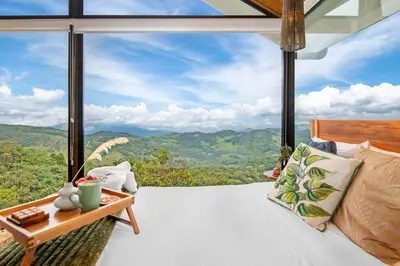 a bedroom with a bed and a view of the mountains at Aves Monteverde Eco Lodge con jacuzzi in La Cruz