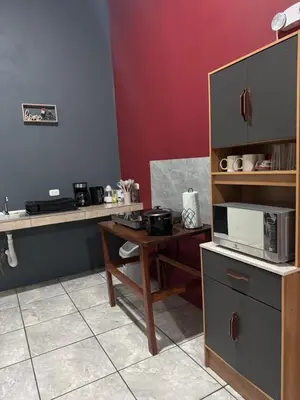 a kitchen with a table with a microwave and a counter at Casa Colibrí Encanto Rústico y Comodidad Moderna -La Fortuna in Fortuna