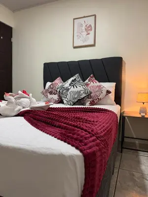 a bed with a red blanket and pillows on it at Casa Colibrí Encanto Rústico y Comodidad Moderna -La Fortuna in Fortuna