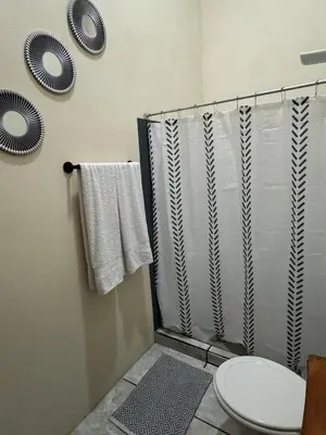 a bathroom with a shower and a toilet and towels at Casa Colibrí Encanto Rústico y Comodidad Moderna -La Fortuna in Fortuna