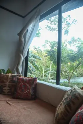 a couch in a room with a large window at Jungle house in Santa Teresa in Santa Teresa Beach