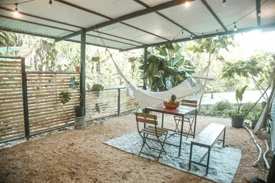 a patio with a hammock and a table and chairs at Jungle house in Santa Teresa in Santa Teresa Beach