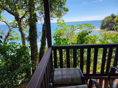 a balcony with a bench and a view of the ocean at Cabinas La Parcela in Dominicalito