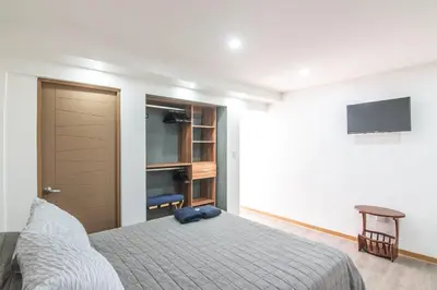 a bedroom with a bed and a tv on a wall at Japandi Tropical Stay in Puntarenas