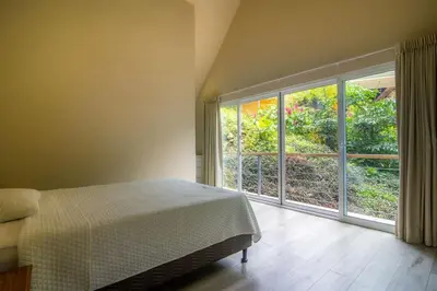a bedroom with a bed and a large window at Modern 2BR Home in Central Manuel Antonio! in Quepos