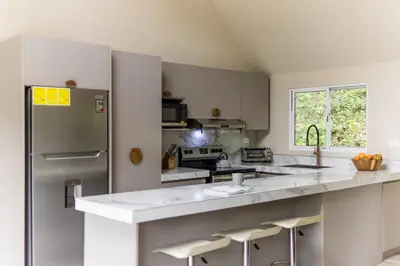 a kitchen with a stainless steel refrigerator and white cabinets at Modern 2BR Home in Central Manuel Antonio! in Quepos