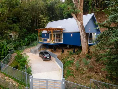 a blue house with a car parked in front of it at Modern 2BR Home in Central Manuel Antonio! in Quepos