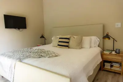 a bedroom with a white bed with a television on the wall at Modern 2BR Home in Central Manuel Antonio! in Quepos