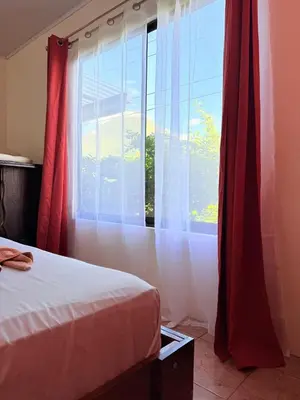 a bedroom with a bed and a window with red curtains at Estancia Rincón Verde in Fortuna