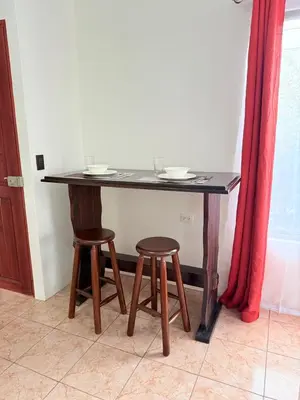 a table with two stools and a table with plates on it at Estancia Rincón Verde in Fortuna