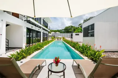 an outdoor swimming pool with chairs and a table at Nomad Containers - Adults only in Tamarindo
