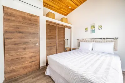 a bedroom with a white bed and a wooden door at Macondo Ecolodge Alpinias - Veranera in Coco