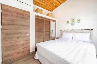 a bedroom with a white bed and a wooden door at Macondo Ecolodge in Coco