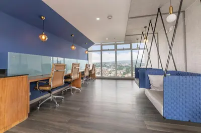 an office with blue walls and chairs and windows at Urban Breeze iFreses, 10th floor! AC, TV and Pool in Guayabos