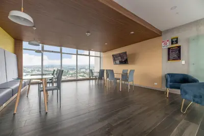 a dining room with a table and chairs and windows at Urban Breeze iFreses, 10th floor! AC, TV and Pool in Guayabos