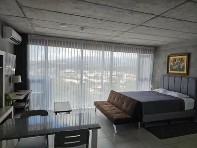 a bedroom with a bed and a desk and a table at Urban Breeze iFreses, 10th floor! AC, TV and Pool in Guayabos