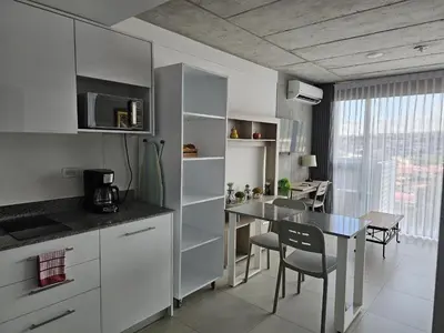 a kitchen with white cabinets and a dining table at Urban Breeze iFreses, 10th floor! AC, TV and Pool in Guayabos