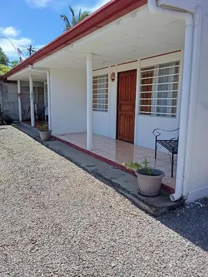a white house with a porch with a bench at Apartamentos y Cabinas Geckos in Sardinal